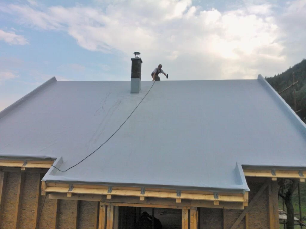 Contractor inspecting a PVC flat roofing membrane