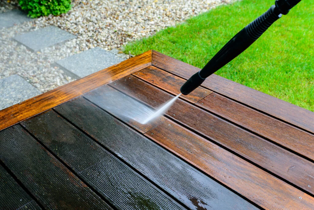 cleaning terrace with a power washer - high water pressure cleaner on wooden terrace surface