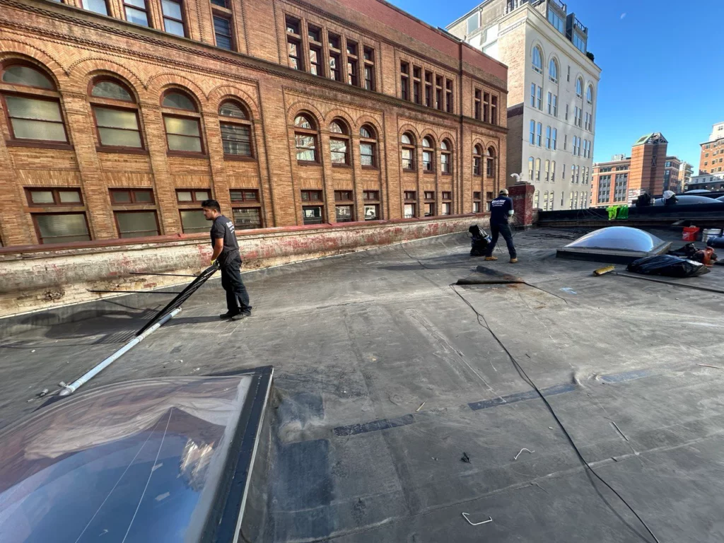 ID Flat Roof team removing the old EPDM layer as part of the roof replacement project at 13 Stanhope St., Boston