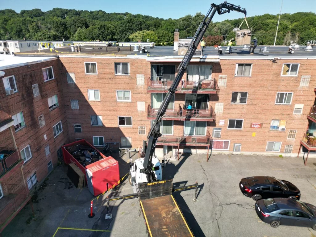 Logistics in action: A crane carefully hoists roofing materials onto the 790 Hyde Park Ave building, ensuring a smooth and efficient installation process.