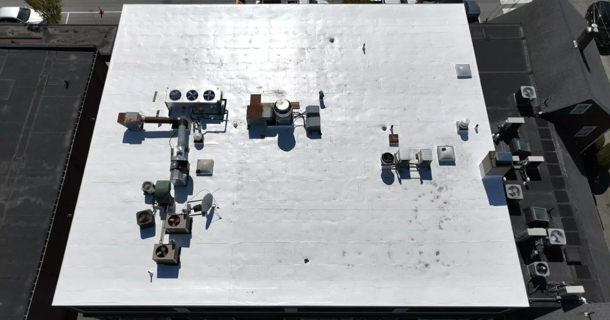 Top-down view of a white flat roof with rooftop HVAC units on a mixed-use building in Lexington, MA